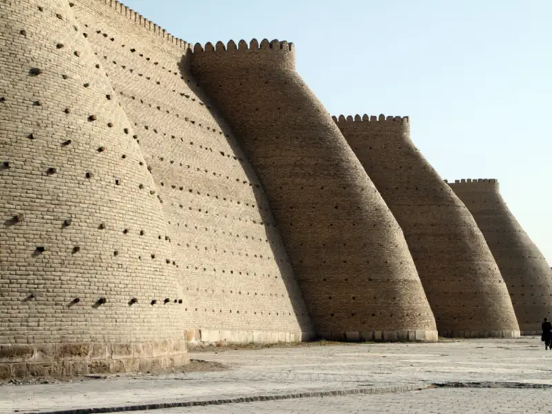 Massive sloping mud-brick fortress walls under a clear sky
