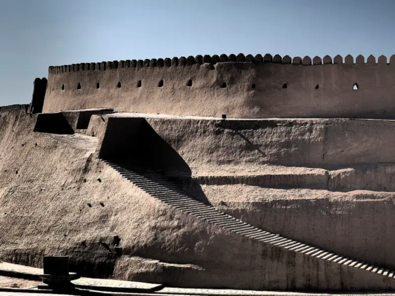 Long crenellated mud-brick wall in low sunlight
