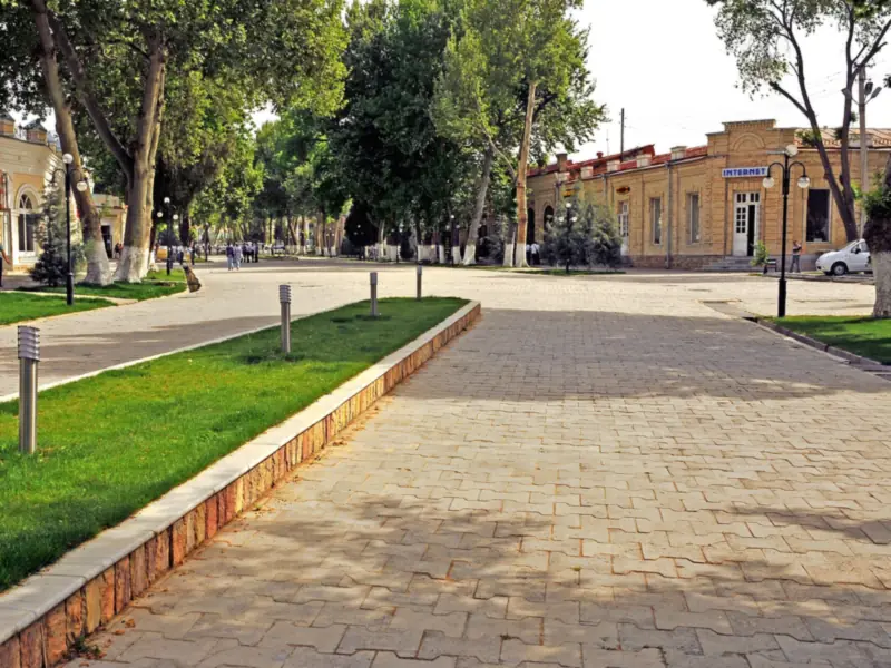 Tree-lined pedestrian avenue beside low colonial-era buildings